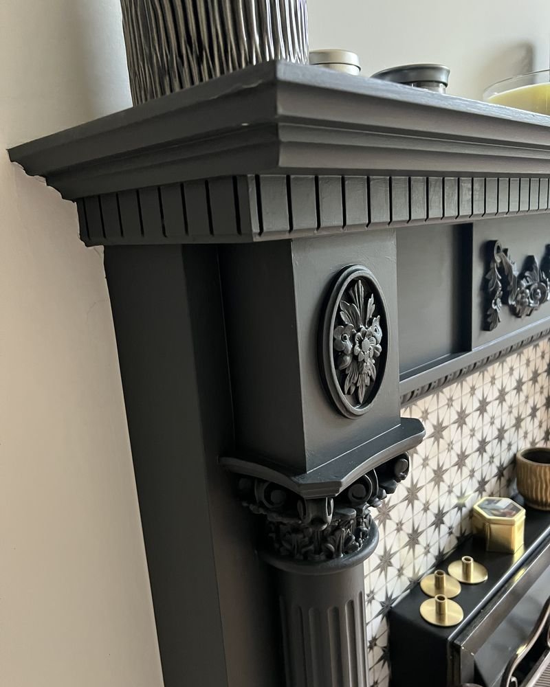 An ornate period fireplace and cornice painted in deep grey