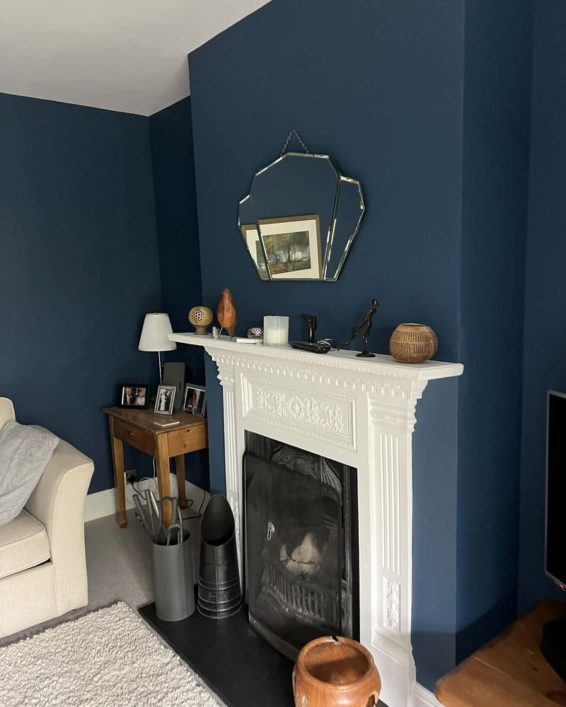 A living room painted deep navy around a white fireplace surround