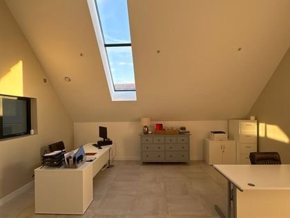 A loft office with sloped ceilings and skylight, freshly painted