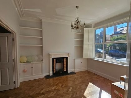 A Victorian living room with alcove cupboards, fireplace and parquet floor
