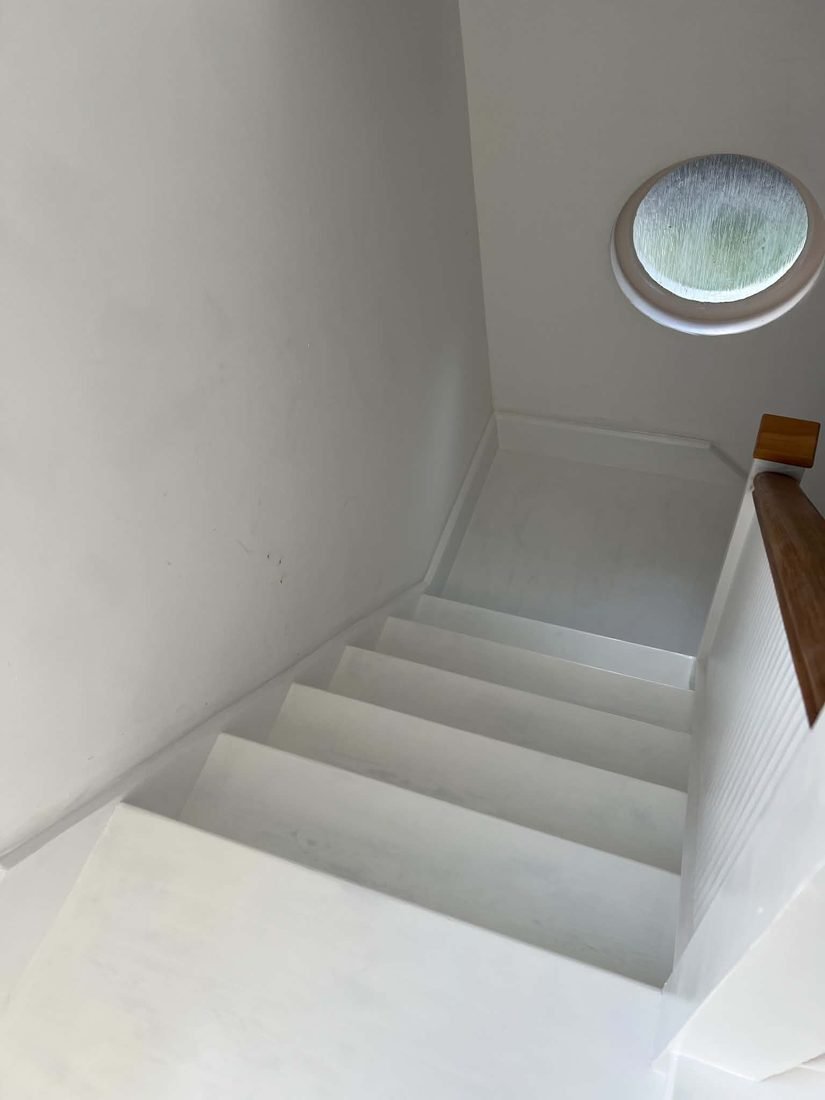 The finished staircase repainted, below a round porthole window