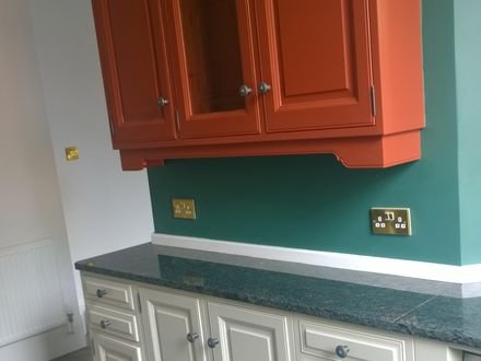 A kitchen hand-painted in cream with a terracotta canopy