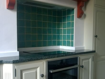 Painted kitchen units with a green tiled splashback