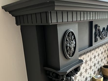 An ornate period fireplace and cornice painted in deep grey