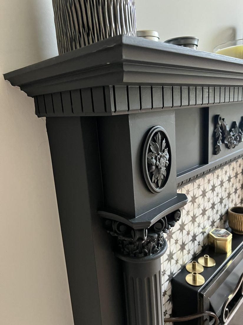 An ornate period fireplace and cornice painted in deep grey