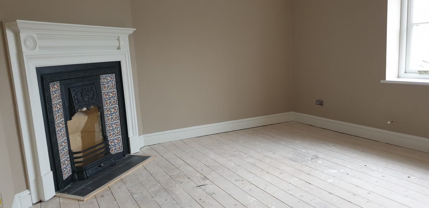 The same room re-plastered and painted around a white fire surround with a cast-iron insert