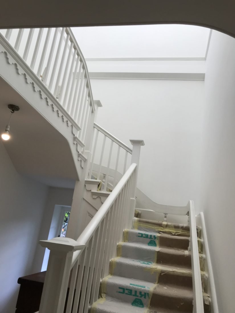 The same stairwell re-plastered and painted, with the balustrade back in