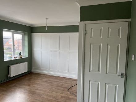 White wall panelling below a deep green wall