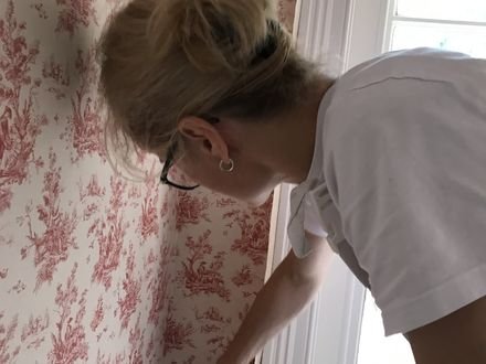 Hanging toile wallpaper by hand in a cloakroom